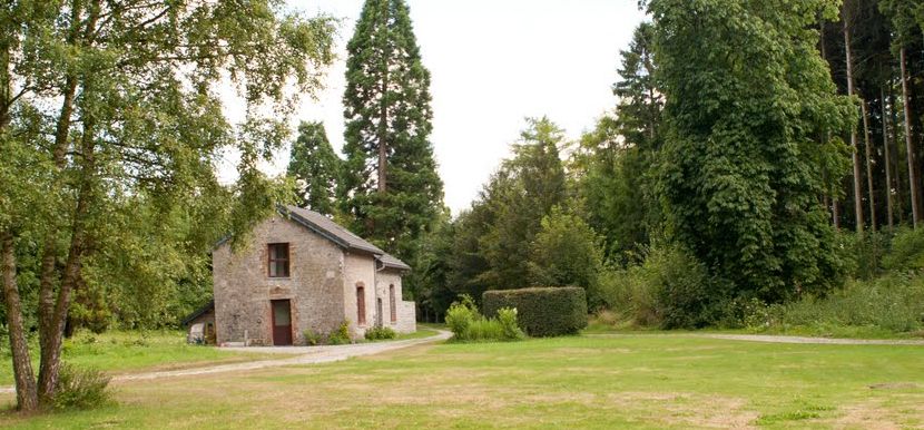 La maison au milieu de la prairie, entourée de grands arbres