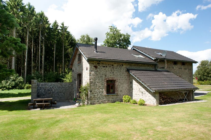 La maison en pierre du Gîte de la Forge et sa pelouse, en lisière de bois